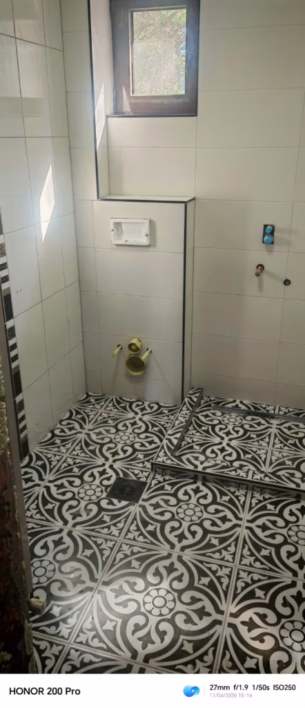 Kupatilo u Surčinu sa belim zidnim pločicama i crno belim dekorativnim podom