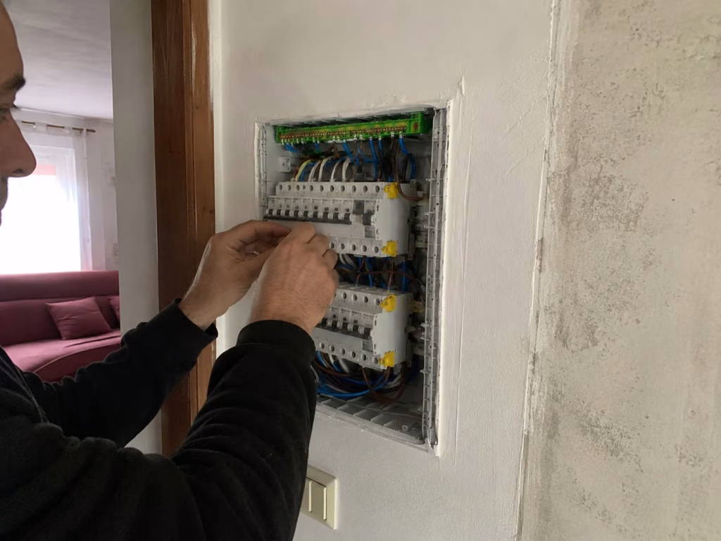 Električar u Barajevu podešava automatske osigurače u otvorenoj razvodnoj tabli porodične kuće.