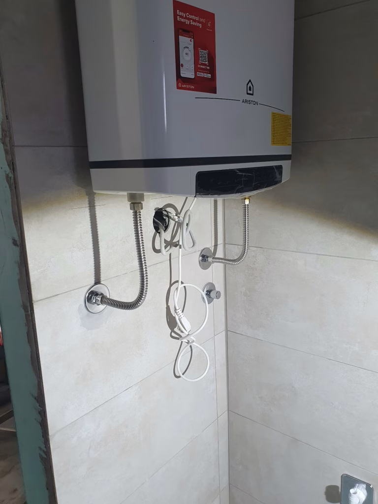 Montiran zidni bojler sa fleksibilnim crevima i ventilima u kupatilu na Voždovcu.